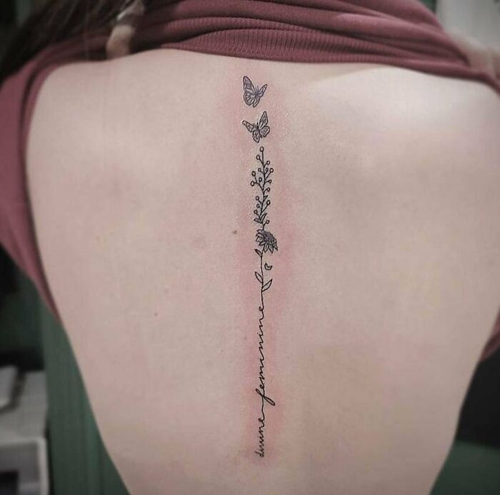 Elegant spine tattoo with butterflies and floral design.