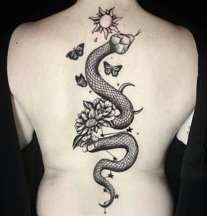Snake spine tattoo with floral and butterfly design.