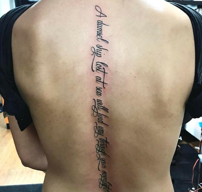 Elegant script spine tattoo on a person's back, showcasing intricate design work.