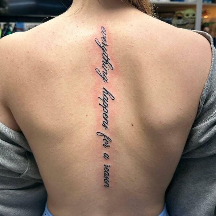 Beautiful spine tattoo with script "everything happens for a reason" on a woman's back.