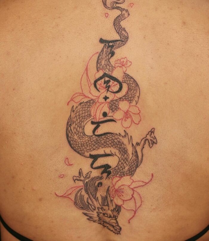 Intricate spine tattoo featuring a dragon and floral elements, showcasing beautiful tattoo artistry.
