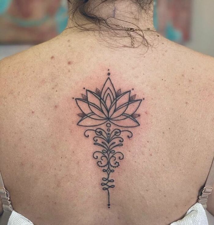 Elegant lotus spine tattoo design on the back, featuring intricate line work and detailing.