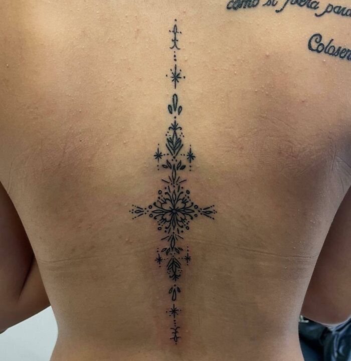 Elegant spine tattoo with intricate symmetrical design showcasing beautiful body art.