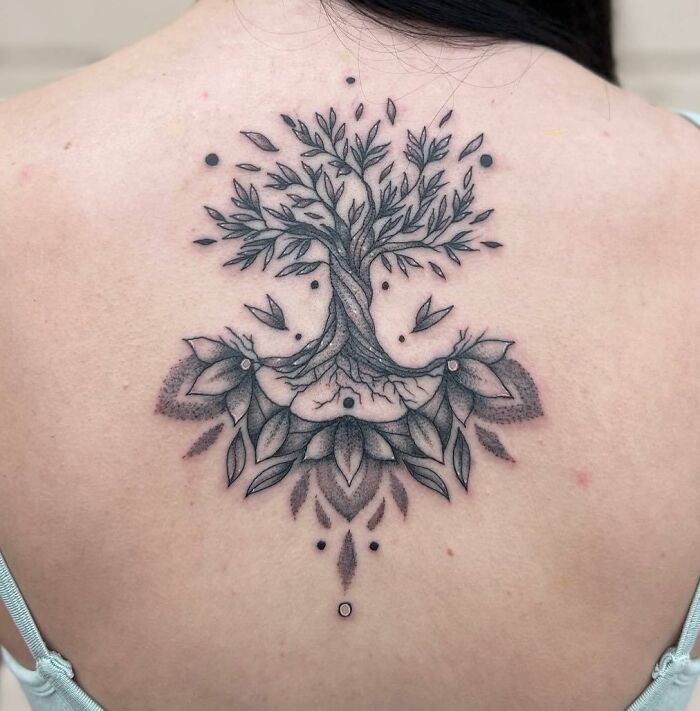 Tree-themed spine tattoo with intricate details and decorative patterns.