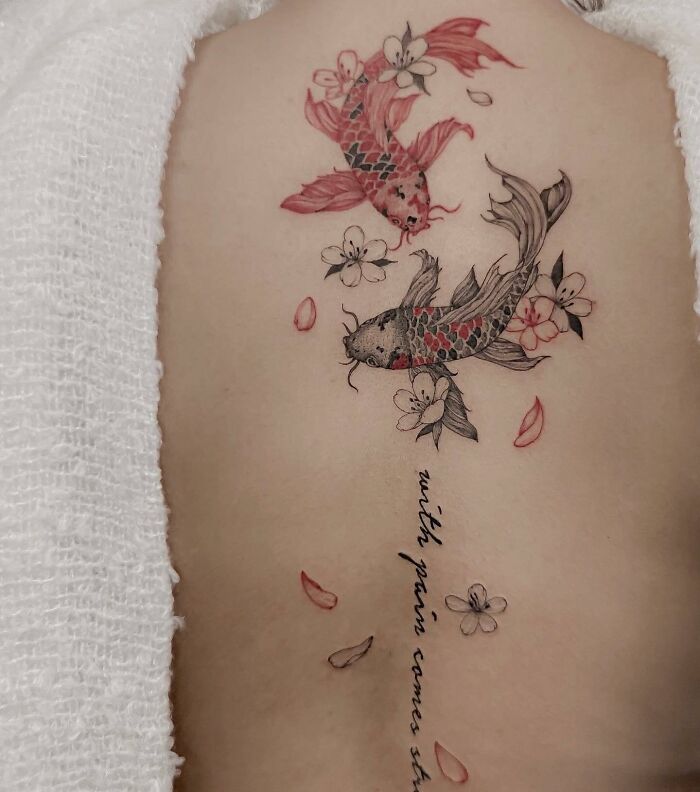 Koi fish and floral spine tattoo with script detail on a person's back.