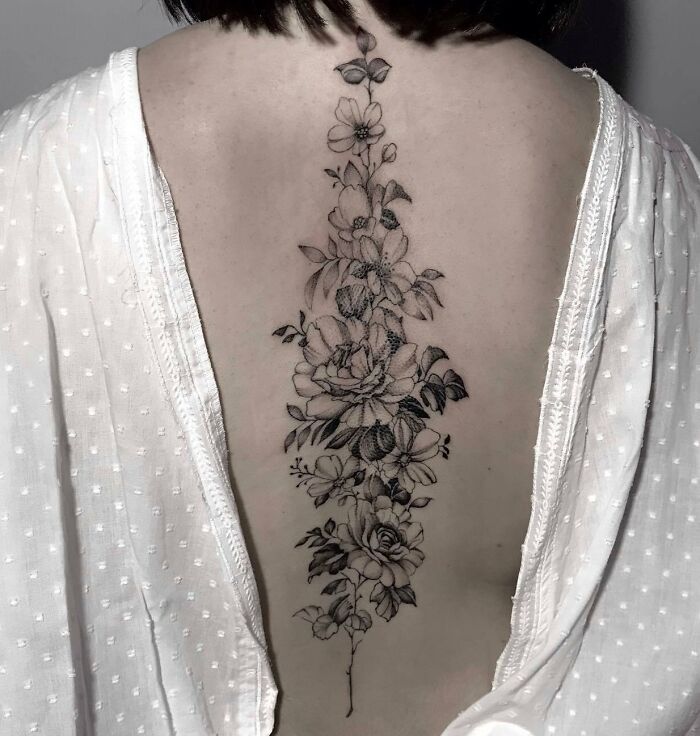 Floral spine tattoo design on a person's back, showcasing intricate detailing and elegance.
