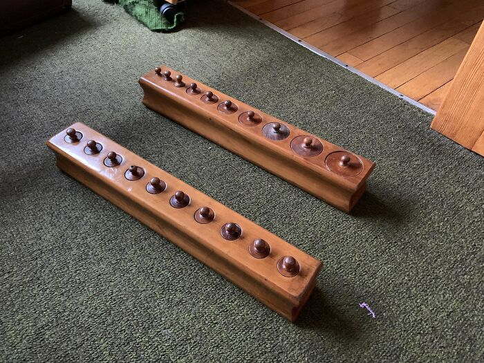 Two Wooden Blocks Inset With Circular Inserts. In One Block, The Circumferences Of The Pieces Are The Same But Their Heights Vary. In The Other, The Circumferences Vary But The Heights Are Identical. 17” X 3” X 3” / 45cm X 7cm X 7cm