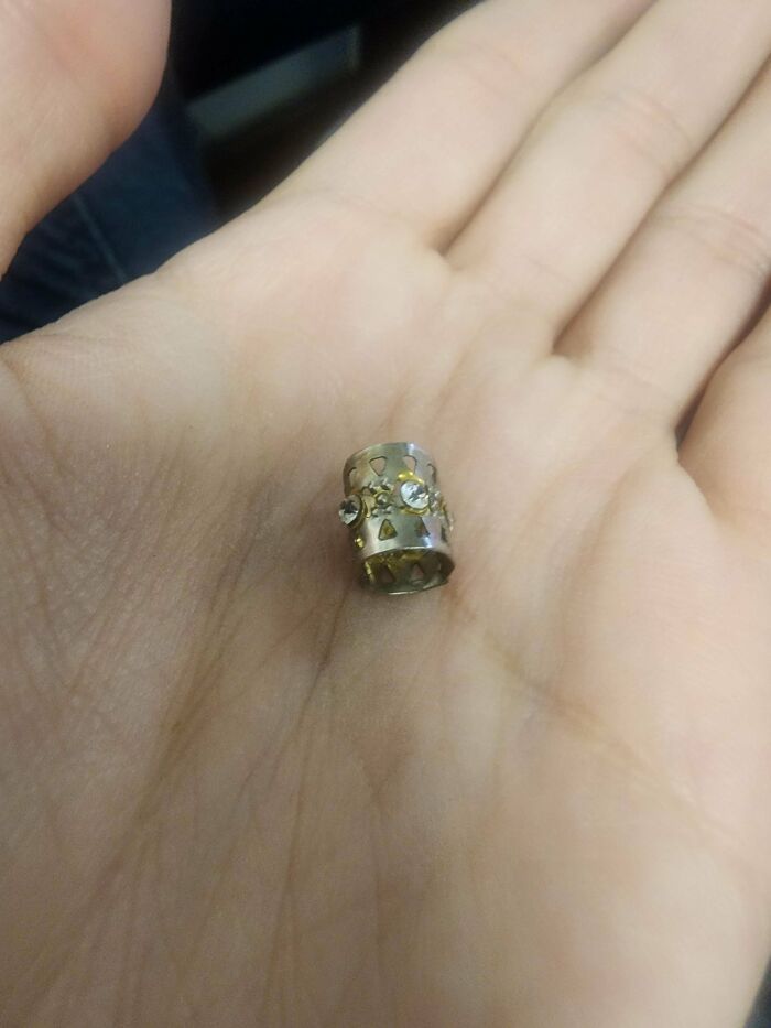 Small mysterious object with decorative holes and gems resting in the palm of a hand, people stumbled upon it.