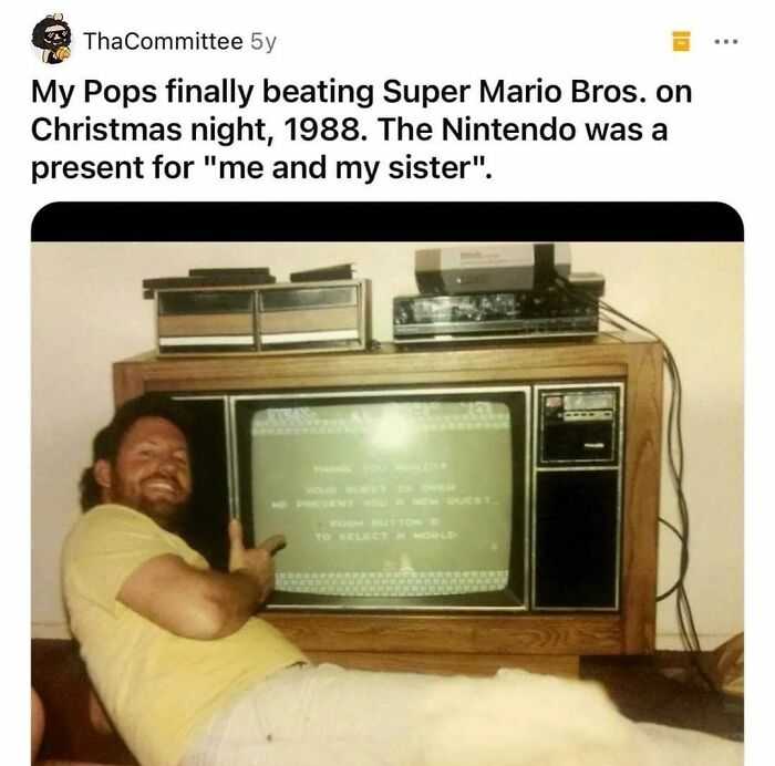 Man smiling and pointing at a vintage 1980s TV playing Super Mario Bros, a nostalgic ’80s and ’90s gaming moment.