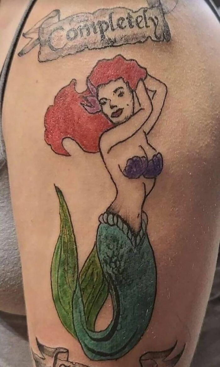 Failed tattoo of a mermaid on an arm, with text above and faded colors.