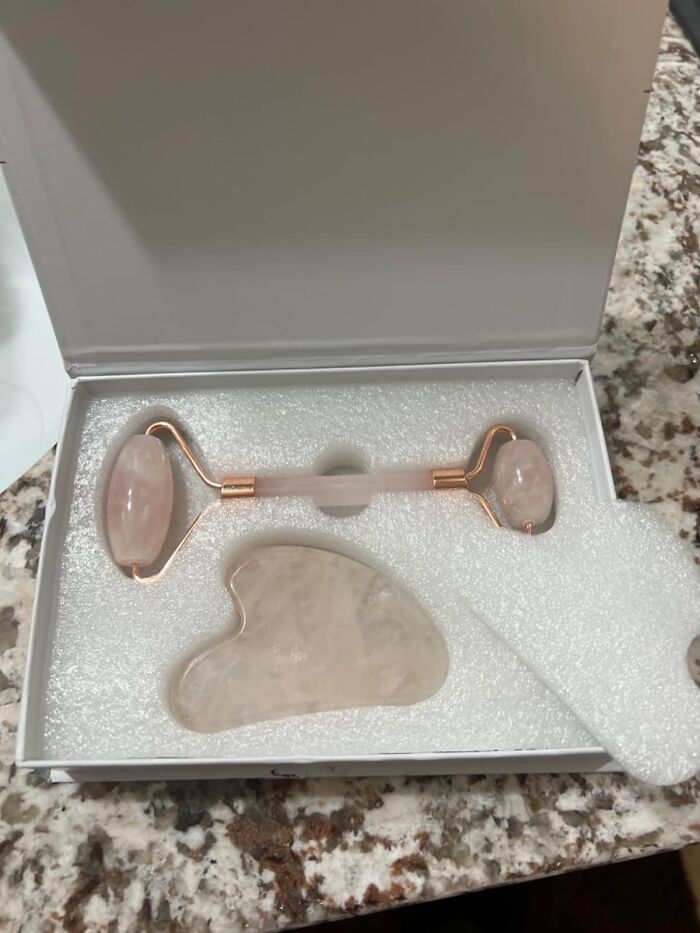 Rose quartz facial roller and gua sha set, ideal for Galentines Day gifts, in an open white box on a marble surface.