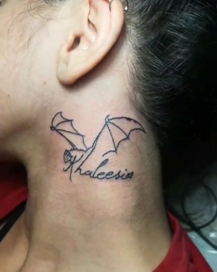Failed tattoo with misspelled word "Khaleesi" and a dragon outline on a person's neck.