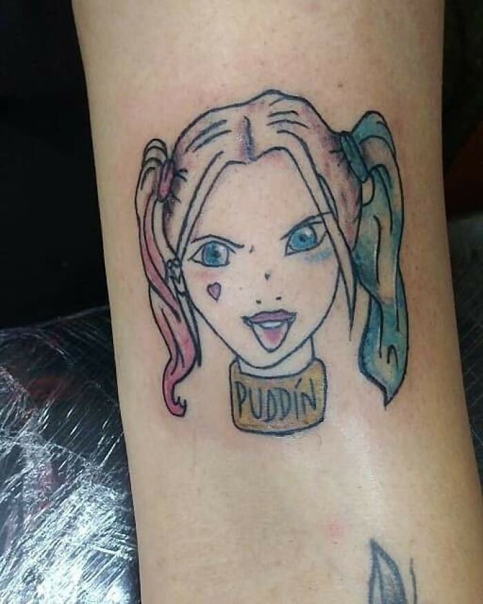 Failed tattoo of a blonde character with pigtails and "Puddin" choker on skin.