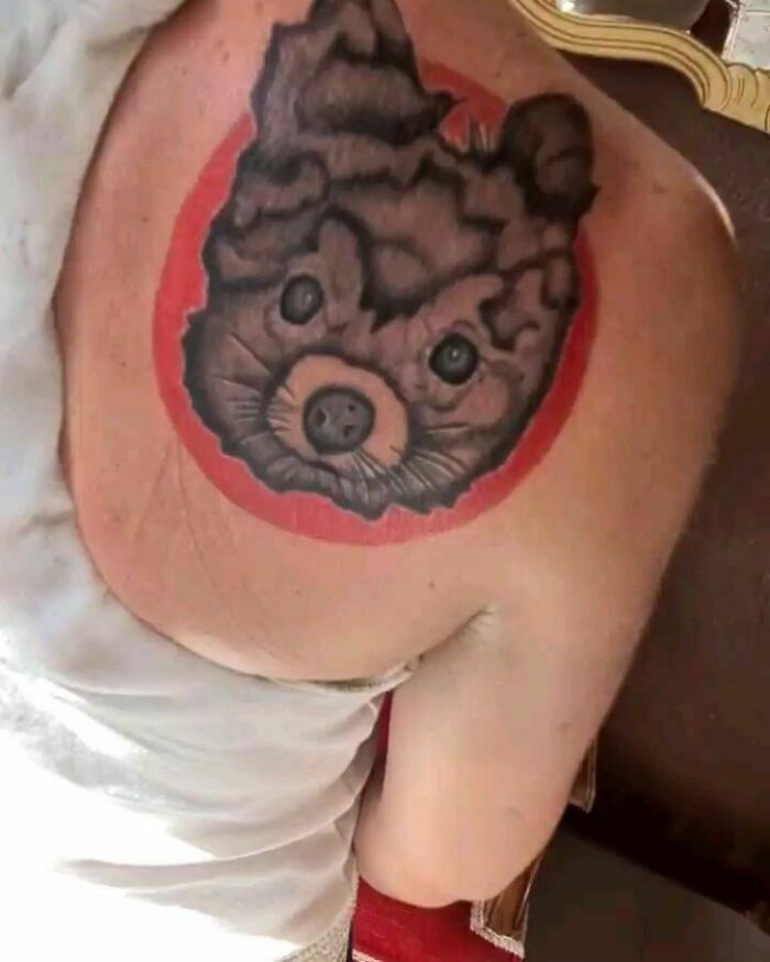 Failed tattoo on a person's back resembling an animal face, surrounded by a red circle.