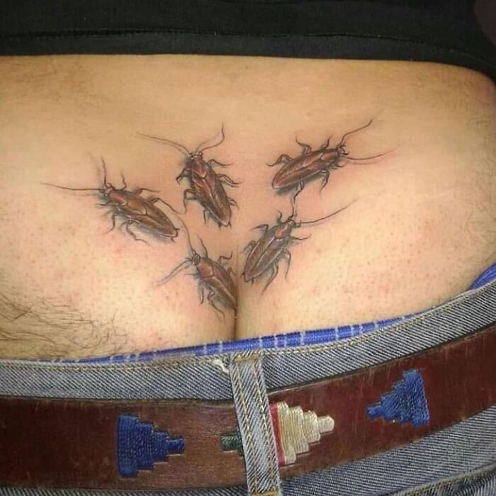 Failed tattoo of realistic cockroaches above jeans waistband.