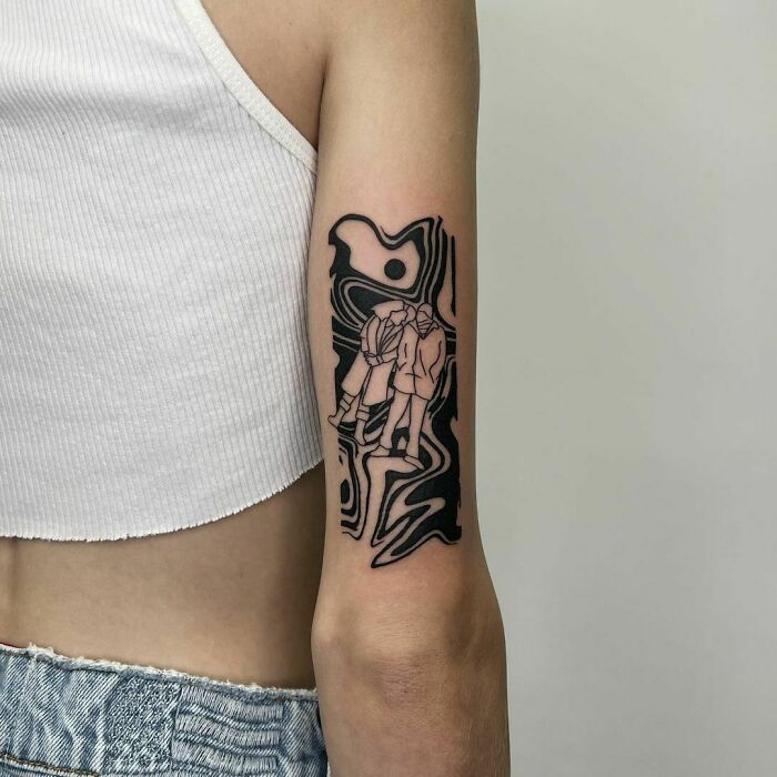Creative tattoo on arm with abstract black patterns and hidden figures in outline.