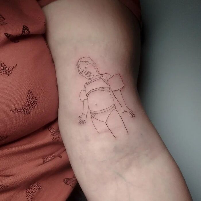 Failed tattoo of a child wearing a swimsuit on a person's arm, illustrating humorous tattoo mistakes.