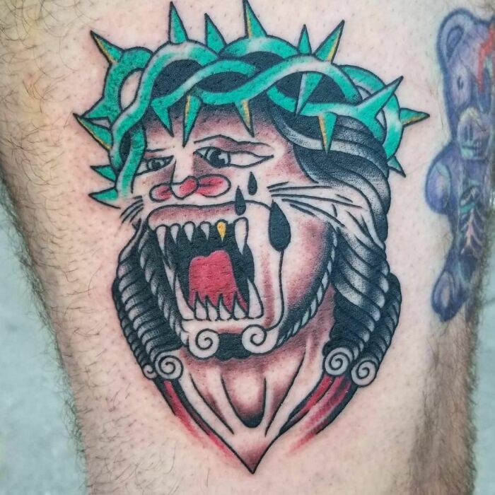 Failed tattoo of a lion with a green crown, showing exaggerated features and tears.