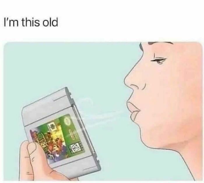Person blowing on a vintage video game cartridge, illustrating nostalgic 80s and 90s gaming memories.