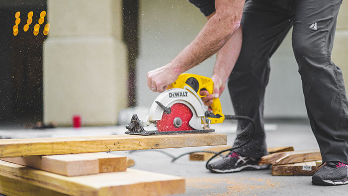 Man using circular saw and cutting a wood plank.
