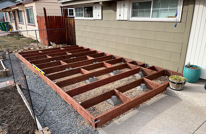Photo of a wooden frame being positioned on the concrete blocks.