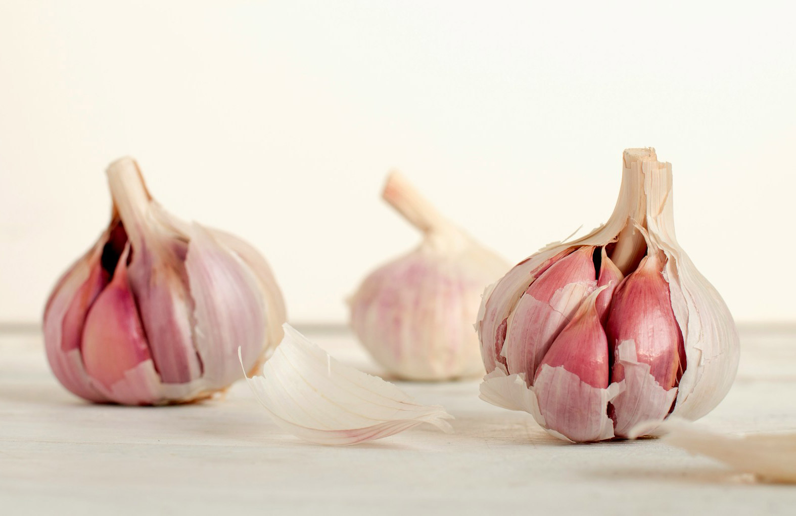 Close-up of garlic bulbs on a light wooden surface, highlighting the question: can dogs eat garlic?