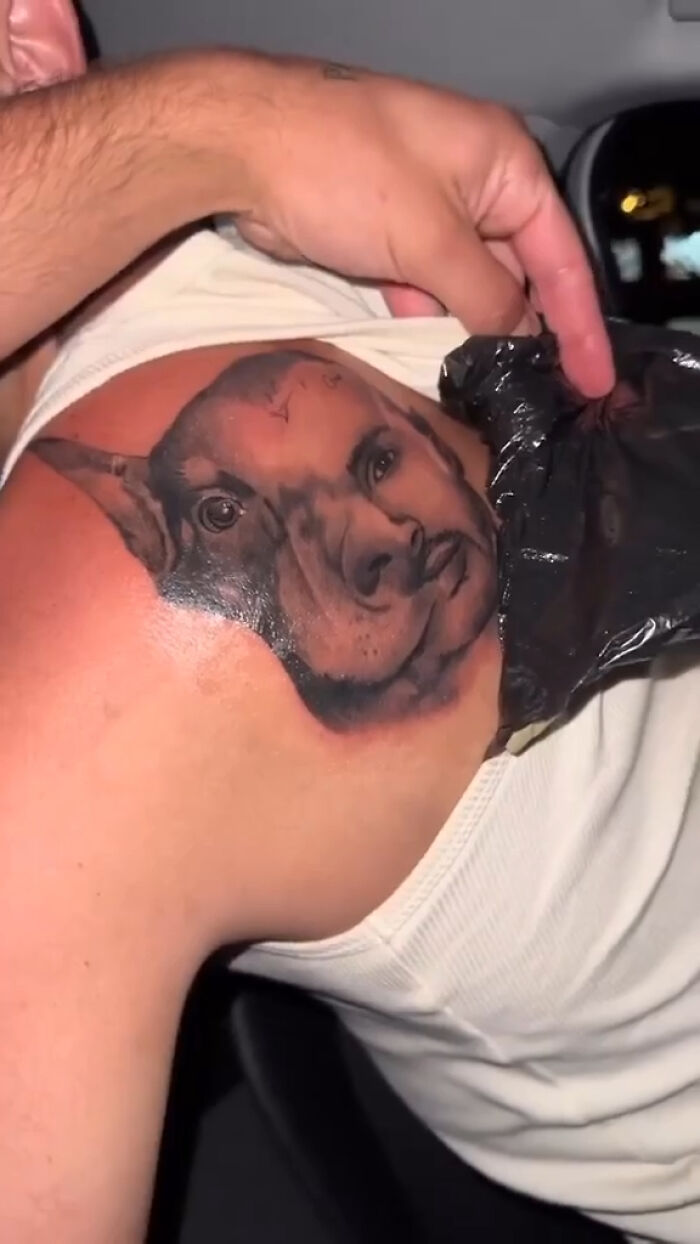 Failed tattoo with a hybrid face design on a person's shoulder being uncovered.