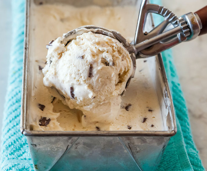 Scoop of vanilla chocolate chip ice cream in metal container, close-up food image representing memorable strangers.