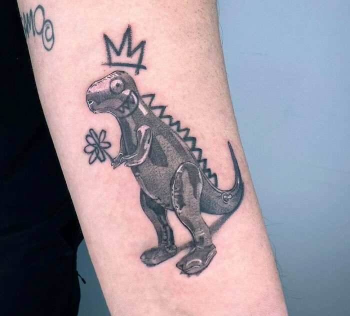 Dinosaur tattoo with a crown and flower on arm, showcasing a creative design.