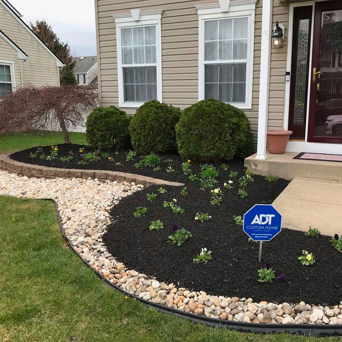 Picture of pebble flower bed edging with small flowers near house