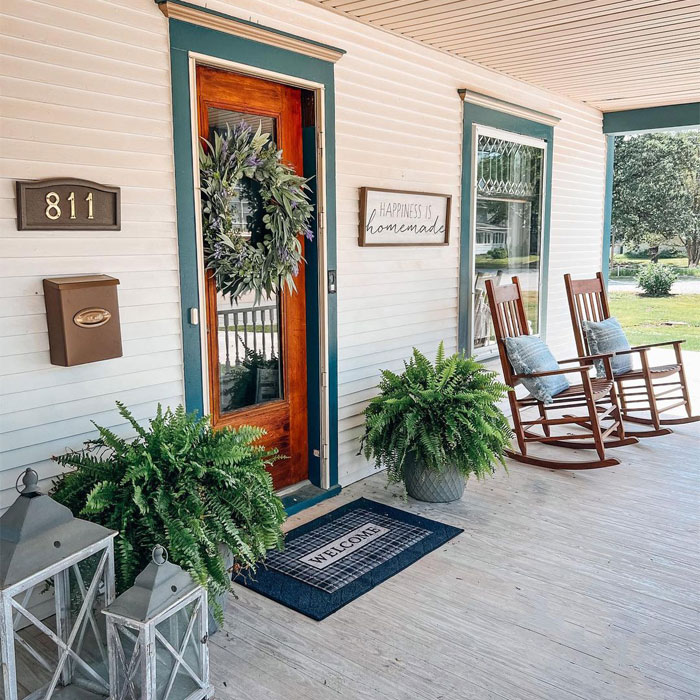 House entrance with house sign and chairs near