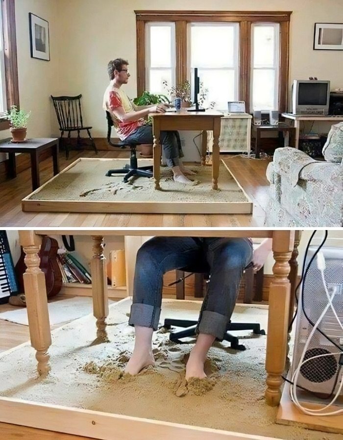 Man working at a desk surrounded by sand in a living room, adding a humorous touch with unexpected decor.
