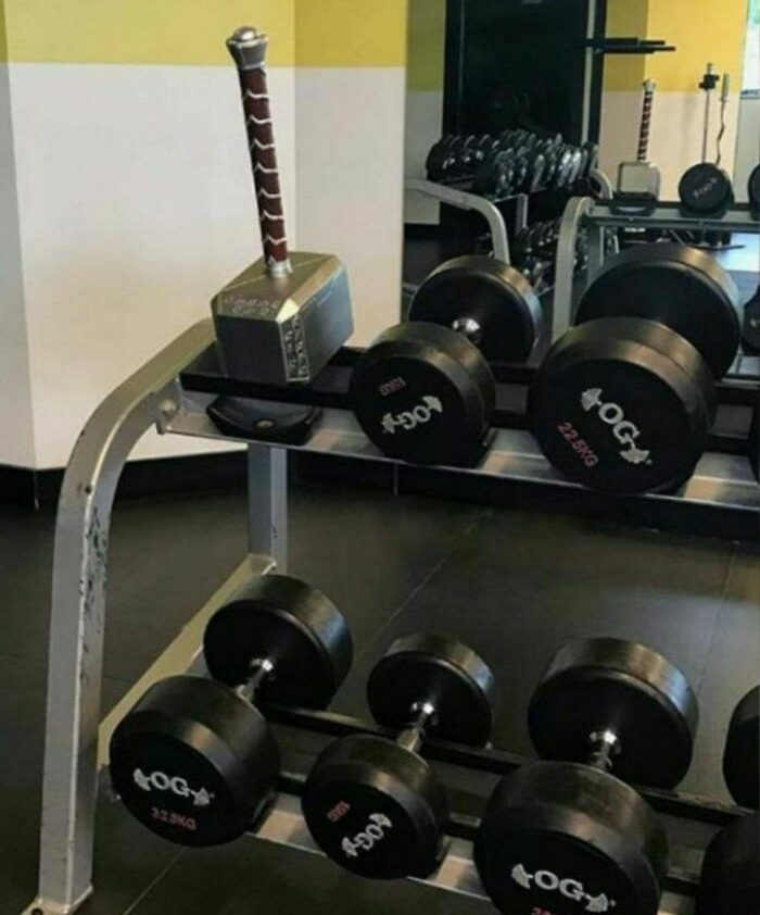 A replica hammer placed among dumbbells in a gym.