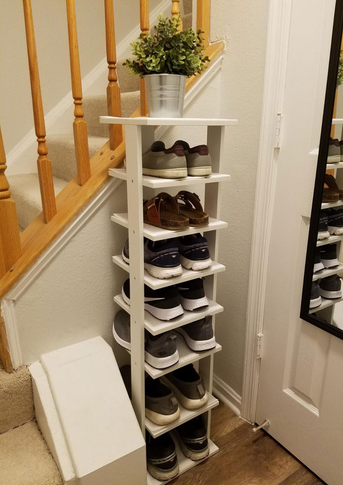 Compact white shoe rack in a tiny apartment entryway maximizing space with vertical furniture for small living areas.