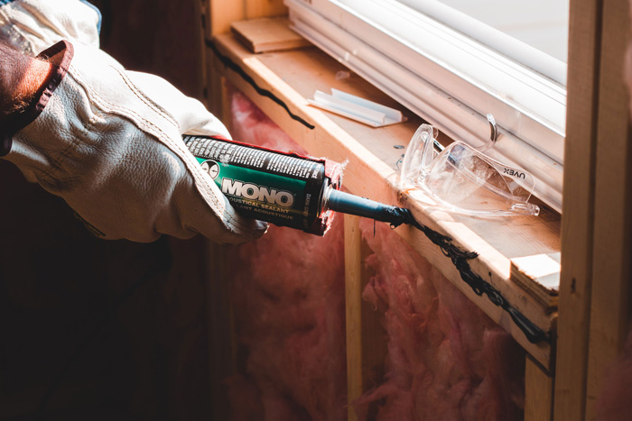 Person applying sealant on the seam of a window