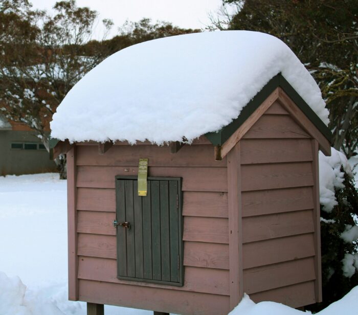 Doghouse covered in snow, illustrating tips to keep your dog warm outside in winter. Doghouse covered in snow, illustrating tips to keep your dog warm outside in winter.