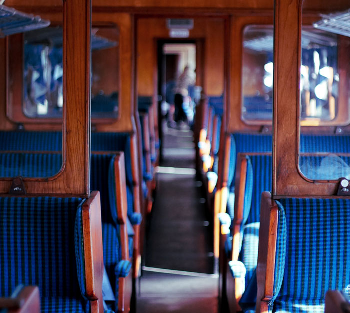 Empty vintage train carriage with wooden panels and blue seats, evoking stories about incredibly memorable strangers.