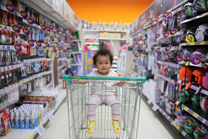 Toddler sitting in a shopping cart in a store aisle, illustrating memorable moments with strangers shared online.