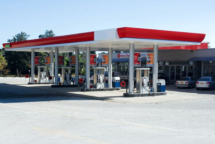 Gas station with multiple fuel pumps under a red and white canopy, illustrating memorable strangers in everyday places.