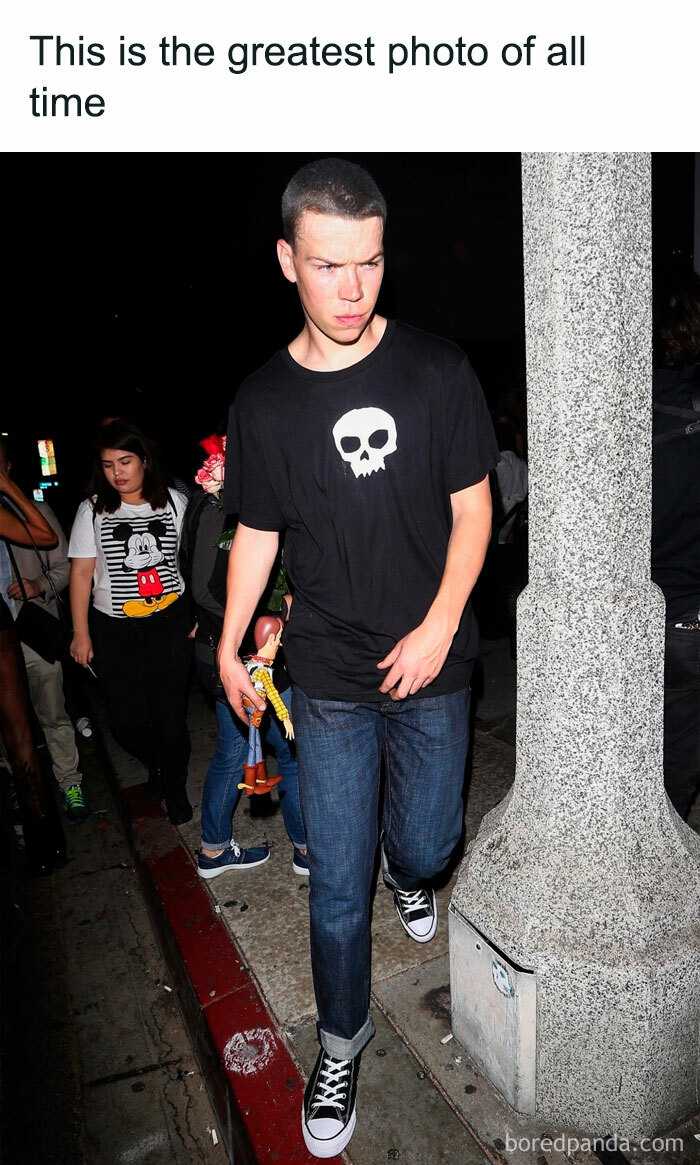 Young man holding Woody toy walking on sidewalk at night, captured in one of the most nostalgic 80s and 90s pics and memes.