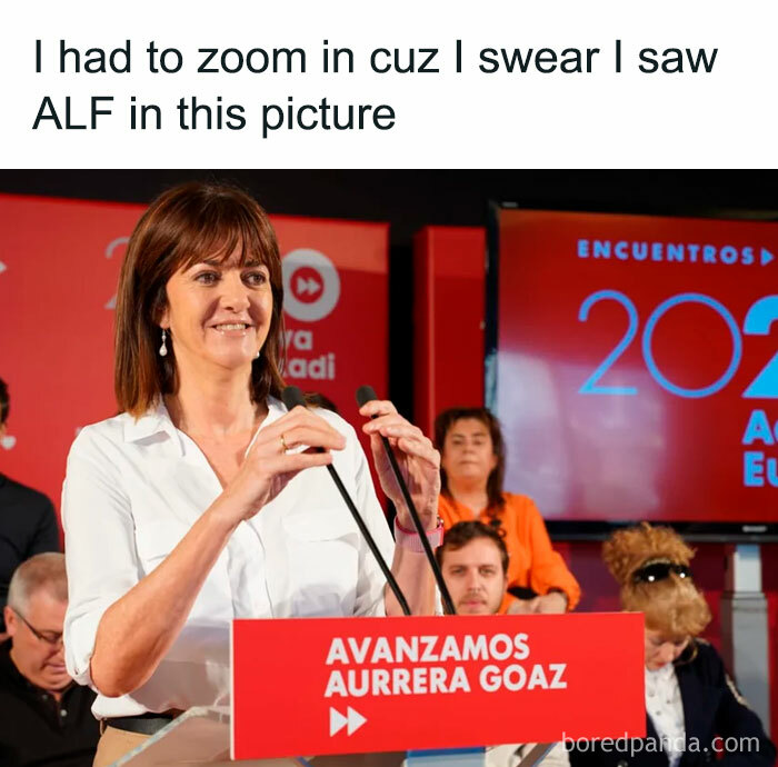 Woman speaking at a podium with a meme referencing nostalgic ’80s and ’90s pics and moments including ALF character.