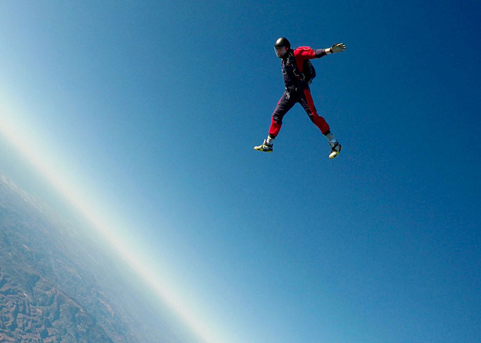 Skydiver in a red-and-blue suit freefalling against a clear blue sky, symbolizing the thrill of laughter and jokes.