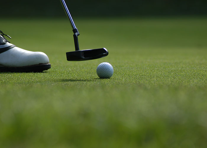 Golf ball being putted on green grass, highlighting a funny moment in sports.