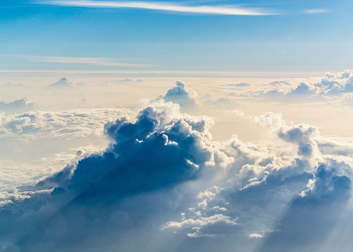 Fluffy clouds in a bright blue sky, illustrating a serene, uplifting atmosphere.