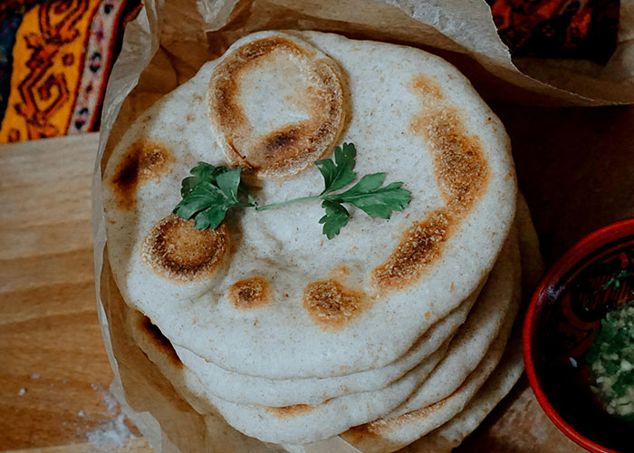 Stack of homemade flatbreads on parchment paper with cilantro garnish.