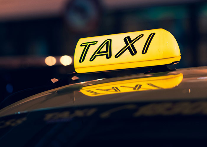 Yellow taxi sign illuminated at night, humorously capturing a city scene.