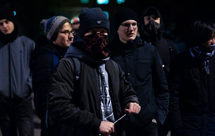Group of people wearing winter clothes and masks, representing memorable strangers sharing stories online at night.