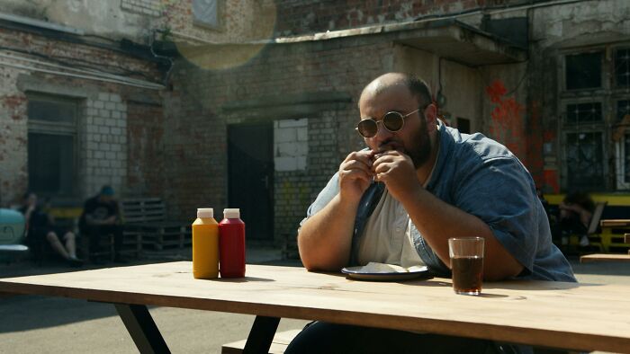 Man at the Wooden Table Eating Hamburger
