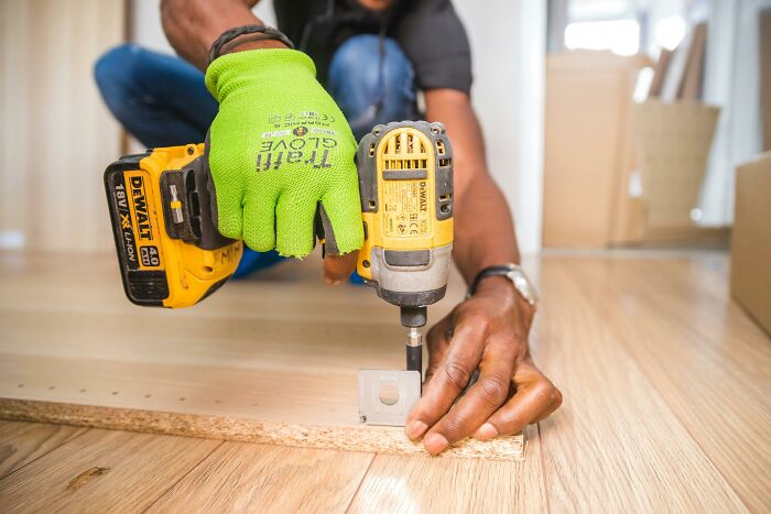 Person using a drill on wood, showcasing basic construction skills.