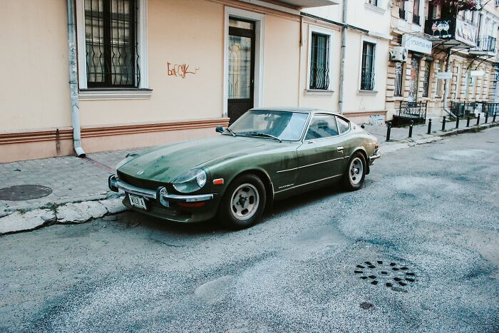 Classic green car parked on a city street, showcasing a vintage vibe.
